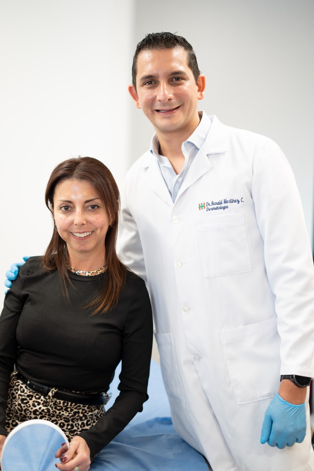 Dr. Ronald Martínez junto a una paciente en consultorio